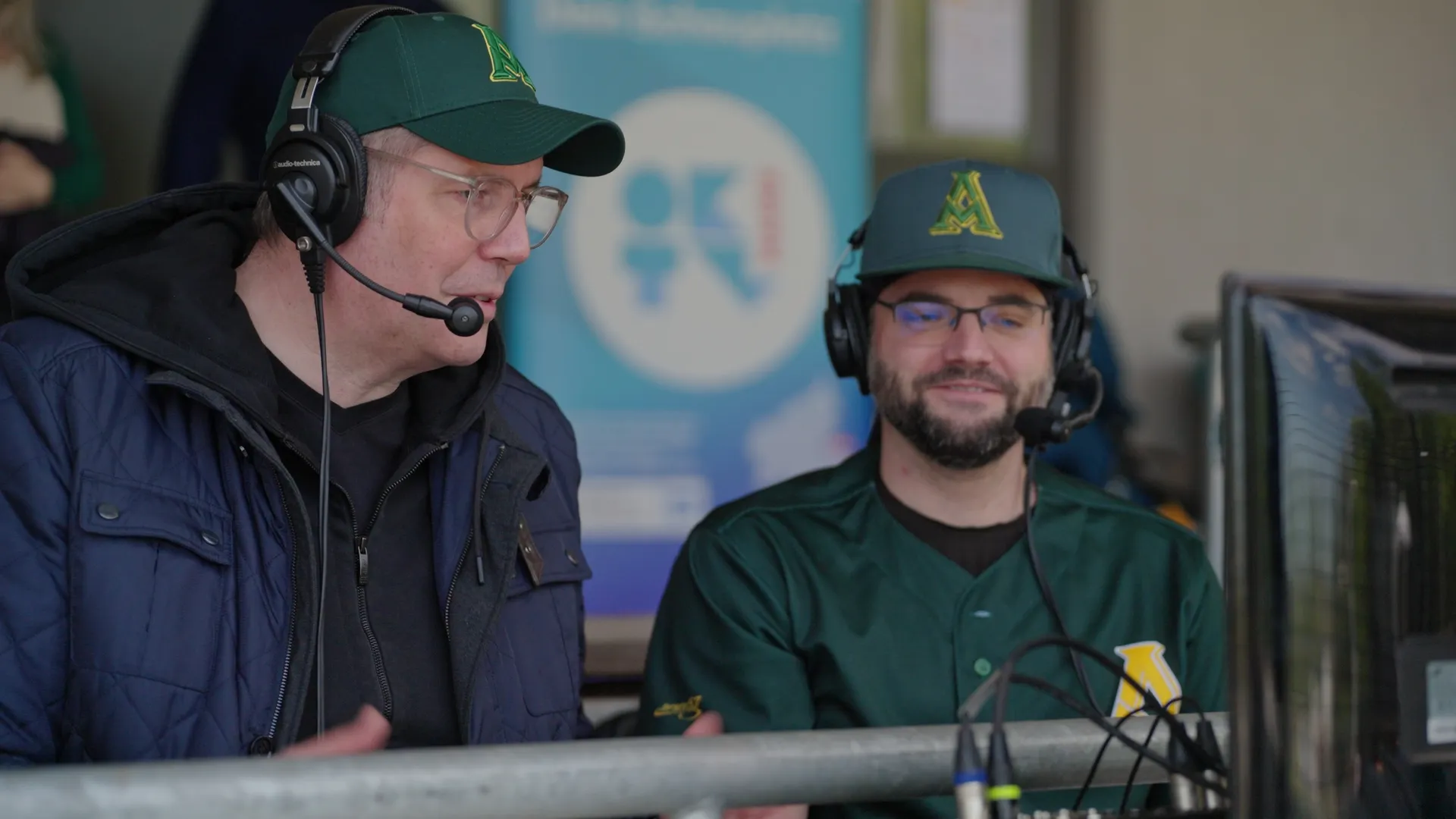 Kommentatoren sitzen an Regiebildschirm